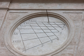 Antique sundial on the wall of the building. Wall clock with Roman and Arabic numerals.