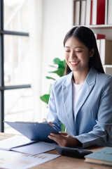 A businesswoman is checking company financial documents and using a tablet to talk to the chief financial officer through a messaging program. Concept of company financial management.