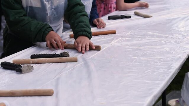 Kids cooking, roll out the dough and making matzah for Jewish holiday Passover Pesach at culinary master class for children outdoor in park. 