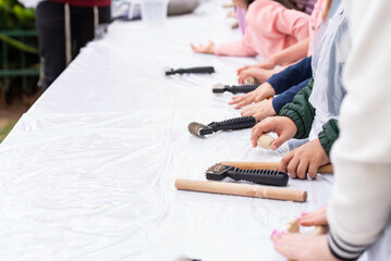 Fototapeta premium Kids cooking, roll out the dough and making matzah for Jewish holiday Passover Pesach at culinary master class for children outdoor in park. 