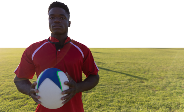 Rugby player holding football at field.