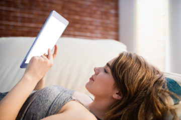 Pretty woman lying on couch using her tablet