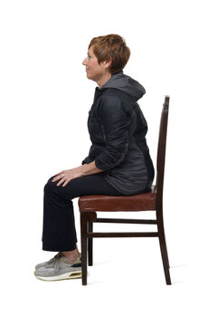 Side View Of A Middle-aged Woman Sitting On A Chair Dressed In Sportswear On White Background