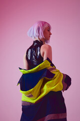 a cyberpunk-style woman poses in a jacket in neon lighting