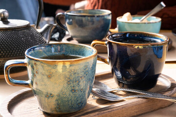 Brewing and Serving Tea. Teapot Poured Green Tea Blue Ceramic Cup on Wooden Cafe Table. Two Pottery Handmade Mugs Early in the Morning. Trendy Authentic Porcelain Set. Breakfast Concept. Tea Time