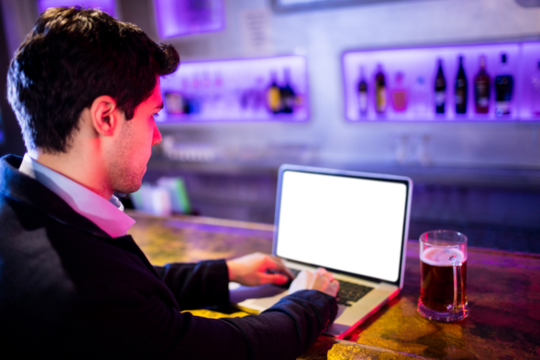 Businessman using laptop by drinking glass - Powered by Adobe