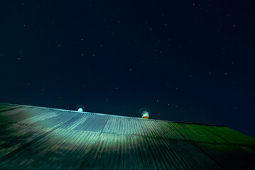 The starry sky over the roof of a country house. Background with millions of stars above the old...