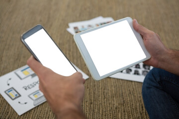Cropped hands of designer holding phone and tablet
