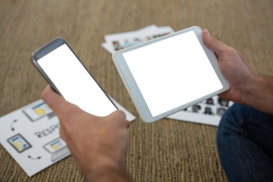 Cropped hands of designer holding phone and tablet