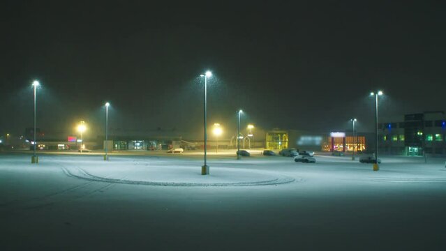 Large parking lot at night in a heavy snow storm. Snowstorm in winter in Halifax, Canada. View of an empty car park with tall night lights and heavy storm snow.