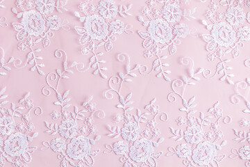 elegant background with a lace white pattern on pink satin. delicate background texture.