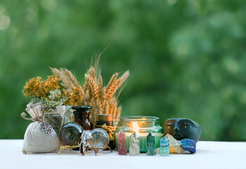witchcraft items, candle, amulets, crystals close up on wooden table, blurred natural background....