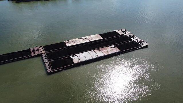 Boat barge load of industrial electricity coal ships tied on the Danube river water. Black coal fossile fuel for power plants in Belgrade, Serbia, Srbija, Ada Huja, Dunav, lignite
