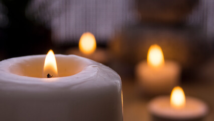 Large lit candle in the foreground and other smaller candles in the blurred background