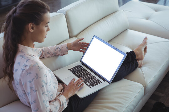 Businesswoman using laptop while resting on sofa