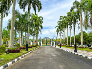 gate and road to a mosque in Brunei Darussalam with blue sky and white clouds in background