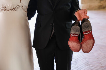 Eleganti scarpe da uomo tenute da uno sposo con su scritto  ironicamente 