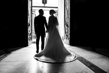 bellissima coppia di sposi ripresa in silhouette mentre esce dalla chiesa