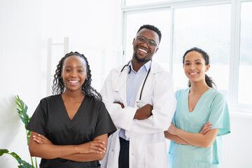 Three medical healthcare professionals stand in a row smiling arms folded