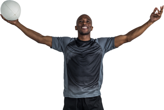 Confident athlete with arms raised holding rugby ball