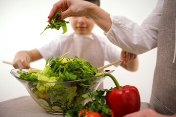 mother and son preparing salad Young woman with fresh vegetables on table in kitchen. High quality photo