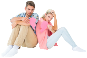 Attractive young couple sitting holding two halves of broken heart