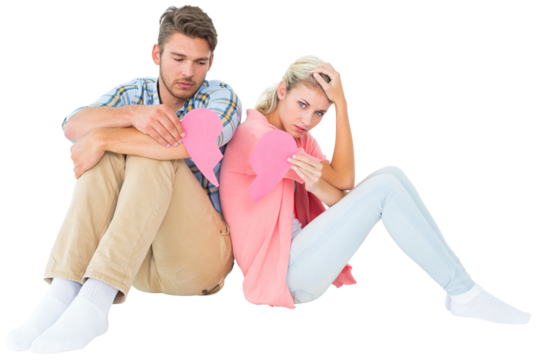 Attractive young couple sitting holding two halves of broken heart