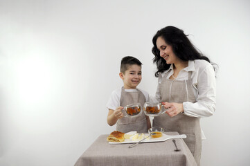 mom and little son spread on cheese honey breakfast healthy food on white background drink tea kitchen apron