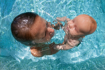 Happy people dive underwater with fun. Funny photo of mother, child in aqua park swimming pool....