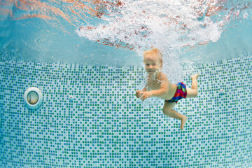 Funny portrait of child learning swimming, dive in blue pool with fun - jumping deep down...