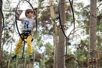 Naklejka na ściany i meble Child in yellow pants climbing in a rope park 