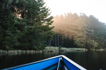 Obraz premium Sunbeam passing through the trees to the river, seen from inside a boat point of view at early morning. POV photograph