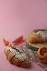 delicious rich fragrant breakfast of a croissant with grapefruit and medicinal rosemary sprigs on a light background