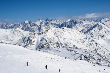 Snowboarders skate on the slope of the mountain. Against the background of beautiful mountains