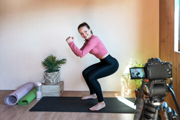 Sporty woman doing sit-ups exercise and recording video for her fitness vlog.