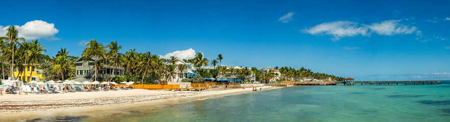 Tropical sandy beach Panorama in Key West, Florida with unidentifiable tourists enjoying the sunny warm weather.