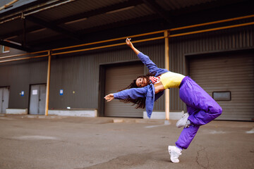 Cool dancer on the street in stylish clothes with american bandana dancing. young dancing woman...