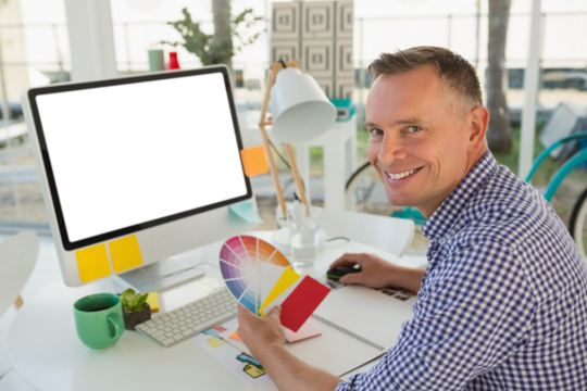 Portrait of businessman with color swatch at desk - Powered by Adobe