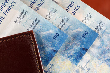 Swiss francs protrude from the wallet