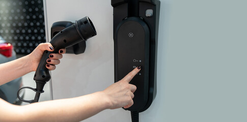 Woman holding plug of electric car charging station	