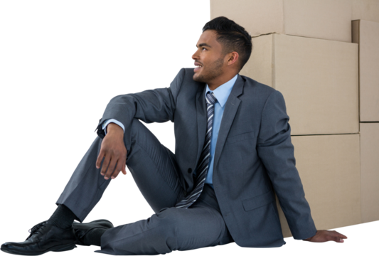 Businessman sitting near cardboard boxes against white background