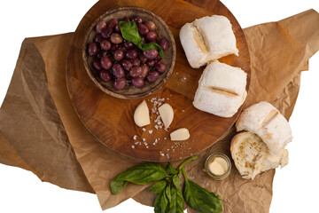 Black olives by garlic and herb by bread on cutting board