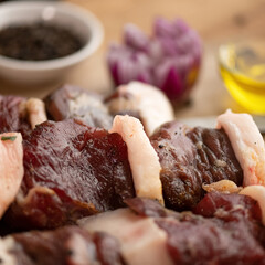 Raw marinated beef skewers are ready for frying. Spices and spices in background on table. Light brown background. Close-up. 