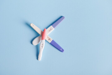 Flat lay composition with pregnancy tests stacked on blue pastel background with copy ad space. Women's health, fertility and rapid pregnancy diagnostics concept
