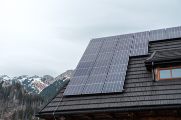 Photovoltaic panels on the roof of a mountain hut. Mountains in the background