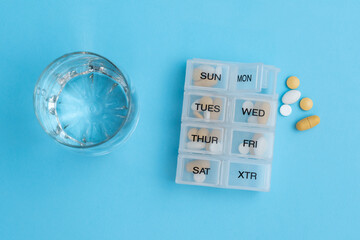 Yellow and white pills in a plastic daily organizer for a week of medication