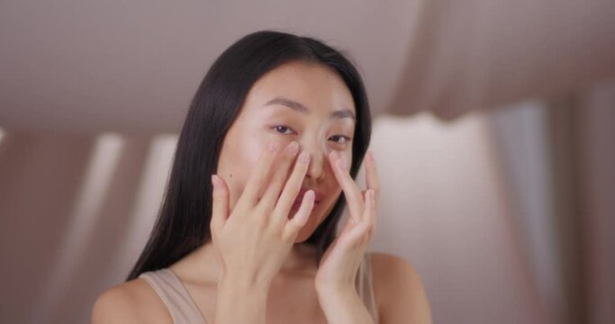 Pretty Asian woman feeling joyful through healthy and clean skin. Good-looking female happy glancing and posing to camera. Touching face and beautiful body. Cosmetology, glamour concept.