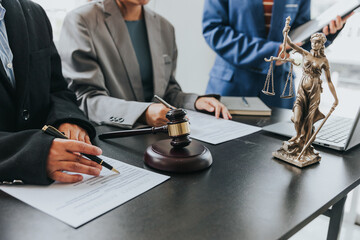Close up of female lawyer writing contract with Judge Havel Brass scale on a table at a law firm law and justice concept.