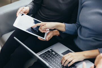 Closeup group of adults friends sitting on couch with hands modern smartphone tablet business startup friendship teamwork concept coworking people project coworking process studio.