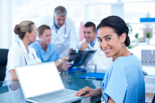 Beautiful smiling doctor typing on keyboard with her team behind